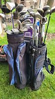 Two golf bags outdoors containing multiple varied golf clubs with visible wear.