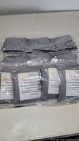 Four grey fabric air purifying bags containing activated charcoal in plastic packaging
