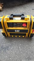 Front view of yellow CAT CJ3000 battery booster with central handle and control panel.