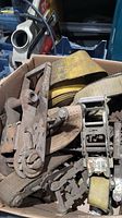 Box containing miscellaneous heavy duty straps and metal ratchet buckles with visible rust and wear.