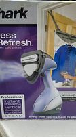 Close-up photo of Shark Press And Refresh garment care system with Heattec WrinkleEraser on box showing handheld steamer device in gray and purple colors and vertical press pad accessory for steaming clothes on hanger.