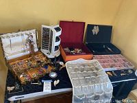 Photo of assorted costume jewelry arranged on trays and jewelry holders including earrings, rings, necklaces, and watches.