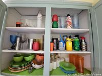 Shelves with assorted plastic and glass cups, bowls, and kids thermos bottles in various colors and designs