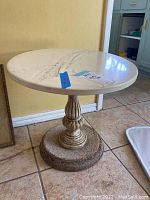 Photo showing the round faux marble tabletop with scratch marks and label tape on top, highlights condition and finish.