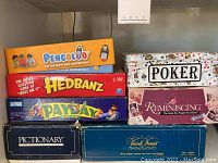 Stacked board game boxes of Pengoloo, Hedbanz, Payday, Pictionary, Poker, and Reminiscing showing front cover art and titles.