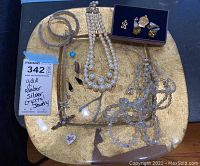 Overview of entire jewelry lot displayed on a gold tray, showing necklaces, pendants, earrings including amber and pearl pieces.