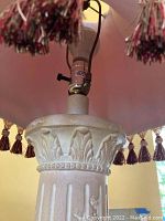 Close-up of the decorative plaster base showing leaf and bead relief patterns on the lamp base.