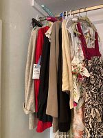 Clothing rack showing a selection of men's jackets and women's dresses hung together in a room corner.