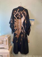 Full view of black kimono hanging on wall showing full embroidered bird and floral design on back