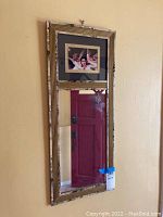 Full view of the wall mirror with the angelic scene above it and reflective chipped red door in mirror.