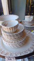 Stack of dinner plates, dessert plates, salad plates and coffee cups with detailed floral pattern on edges and rims
