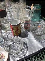 Assorted glassware on white cloth showing Mason jar, mugs, clear glass bowls, pitcher and vases
