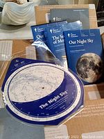 Multiple guidebooks and star charts laid out on a tabletop showing materials related to The Great Courses Astronomy series