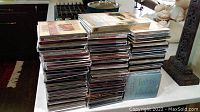 Three stacks of various music CDs on a kitchen counter, showing quantity and size of collection