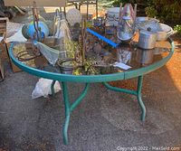 Full view of round glass outdoor table top with metal frame and various household items on top
