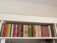 Books arranged on a white bookshelf, mostly spines showing titles in German, including a large set of Brecht plays in beige hardcover.