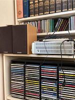 Denon UD-M30 CD player with instruction manual on top alongside two Mission 50 speakers showing wood veneer and logo.