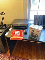 HP ENVY 4520 printer on desk alongside Panasonic phone box and Canon photo paper pack.