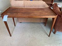 Full view of the wooden side table showing rectangular shape with raised edges on top and four tapered legs.