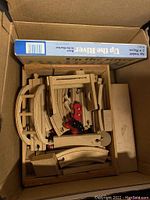 Box containing natural wood curved and straight train tracks and two small red wooden train cars.