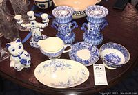 Photo showing all items: two blue and white Delft style three-arm candlesticks, a white ceramic kitten teapot with blue details, an oval blue floral dish, several other small blue and white dishes and bowls, including the Abbey of Holland bowl and Simpsons LTD gravy bowl.
