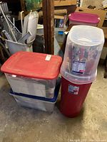 Photo of the three plastic totes and bins containing the lot items including red, blue, and clear lids