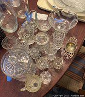 Top view of 15 vintage pressed glass and crystal items including pitchers, bowls, and small containers with various cut patterns.