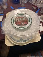 Stack of platters showing top Wedgwood and an assortment of platters beneath, some wrapped in bubble wrap