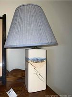 Full view of ceramic base showing the painted abstract landscape design with the pleated fabric shade on top.