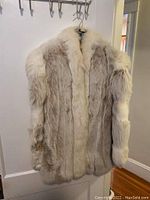 Full view of medium two-toned blonde rabbit fur coat hanging showing fur texture and two-tone colors.