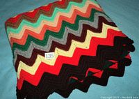 Photo showing folded corner of the colorful chevron pattern afghan with a lot number card 135.