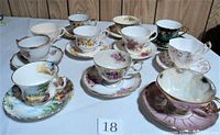Set of 12 assorted vintage fine bone china teacups and saucers arranged on a table, showing different floral patterns and colors with some minor damage.