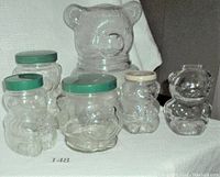 All six clear glass bear containers displayed, showing size and shape variety and green and beige lids.