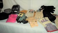 Photo showing gloves and hats overall with some labels visible such as Hercules on gloves and Under Armour on pink cap.