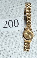 Gold-tone ladies Citizen quartz watch with linked bracelet, day and date window, fluted bezel, and round dial.