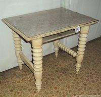 Photo showing side view of the old table with linoleum top, spindle legs, and stretcher connecting legs.