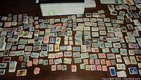 Large assortment of old Canadian stamps spread on a flat surface showing hundreds of individual stamps with various colors and designs.
