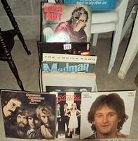 Photo showing front side of various vinyl records in box including Quiet Riot, ABBA, The J. Geils Band, Madman, Queen, Blondie, Robin Williams