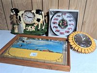 Photo showing four clocks: cow-themed ceramic clock, International Tractor clock in box, sunflower Westclox clock, and rectangular framed mirrored clock with yellow flowers and mill scene.