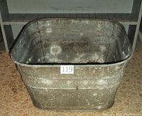 Full exterior view of the old metal wash tub showing aged metal surface and rectangular shape with rounded corners.