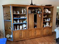Full view of the 5 piece wall unit showing center tambour door, open shelving, and lower cabinet doors with brass handles. Various decorative collectibles displayed on shelves.