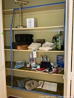 Wide view of hall closet shelves showing cleaning supplies, folded towels, storage baskets, and personal care items