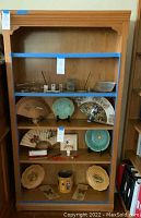 Photo showing the front of the wooden bookcase with multiple shelves filled with various items (not included in sale). It shows the bookcase's design and condition.