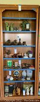 Front view of wooden bookcase filled with various decorative items to show shelving layout