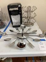 Full lot showing Keurig coffee maker, metal coffee pod holder, and utensil clock on table