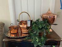 Copper decorative items including lidded urn, bucket with handle, small pot on large tray with silver edge.