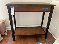 Full view of wood foyer table with dark painted legs and middle shelf