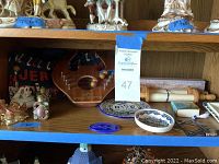 Shelf with various religious decorative items including a wooden Torah scroll replica, decorative plates, and small figurines.