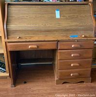 Wooden roll top desk showing front view with closed tambour cover and drawer arrangement.