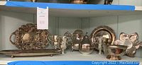 Wide view showing silver plated pieces including teapot, cups, decorative trays, and bowl